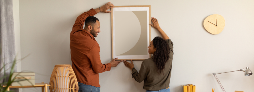 Una pareja cuelga un cuadro en su nuevo hogar